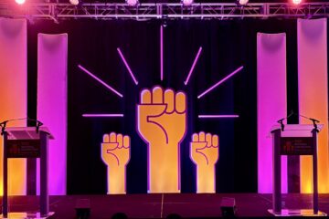 Three fists raised set the backdrop for a colorful convention stage
